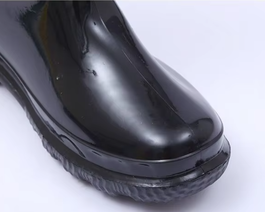 a092bfdc-7822-4703-8756-0930a4d9c5b3_광택이 나는 검은색 웜 PVC 방수 작업화의 둥근 발끝 부분 클로즈업.png